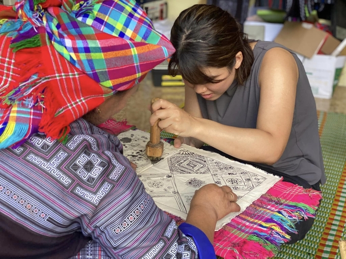 A Chinese visitor is trying painting on fabric. Photo: Thanh Tien.