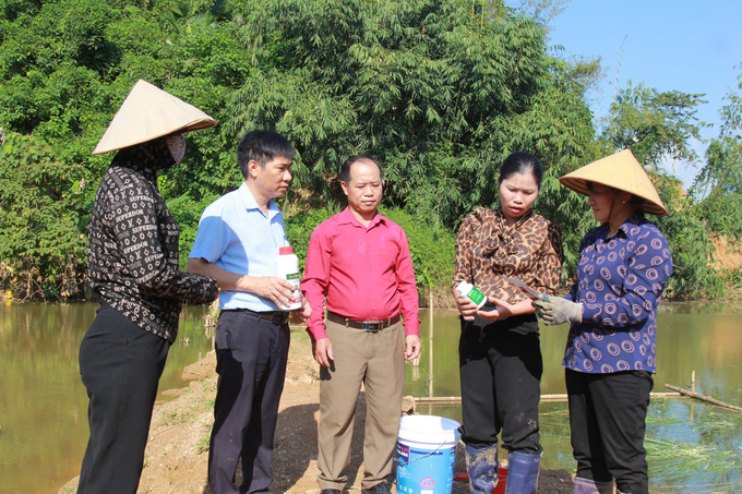 Cán bộ kỹ thuật của Chi cục Thủy sản hướng dẫn người dân các biện pháp xử lí môi trường sau lũ. Ảnh: Thanh Tiến.