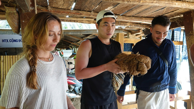 Foreign visitors are shown how to grow flax and weave fabric. Photo: Thanh Tien.