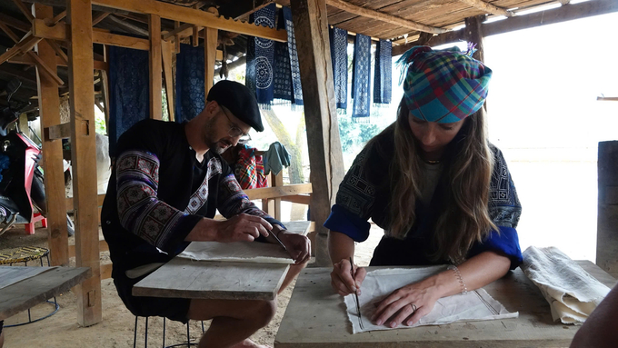 Western visitors are drawing with beewax on fabric. Photo: Thanh Tien.