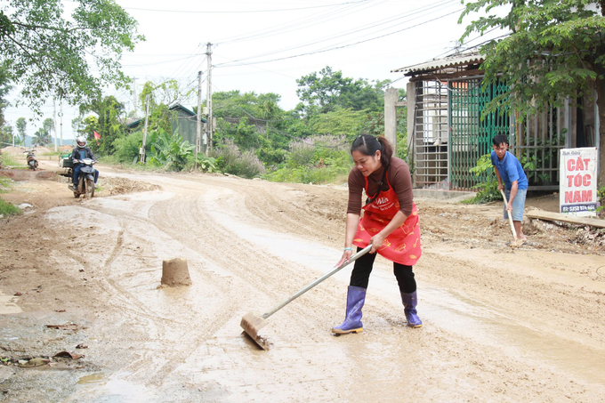 Người dân tự cào gạt bùn trên mặt đường để không tràn vào nhà.