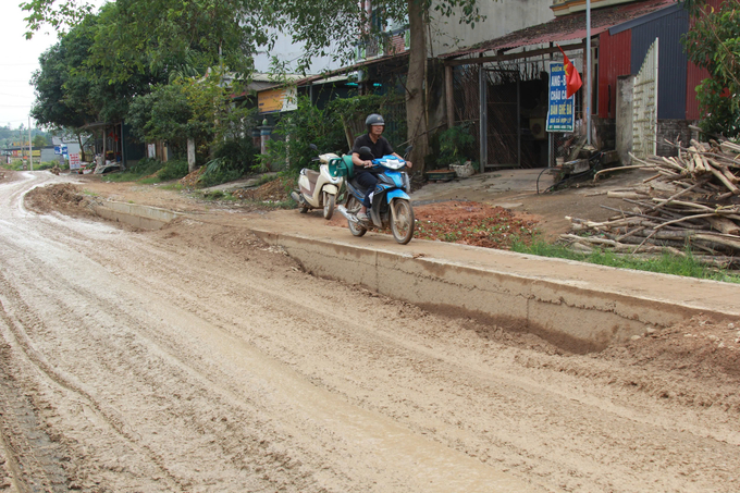 Người dân di chuyển trên phần rãnh tuyến đường đang thi công để tránh bùn đất. 