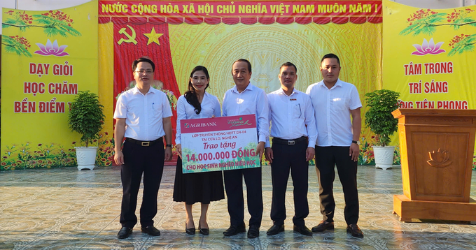 Ông Đỗ Minh Khương - Phó Trưởng phòng Hỗ trợ Phát triển Kinh doanh Văn phòng đại diện Agribank khu vực Tây Nam bộ (ở giữa) - trao bảng tượng trưng số tiền hỗ trợ cho đại diện Ban Giám hiệu Trường THCS Nghi Thủy. Ảnh: MK.