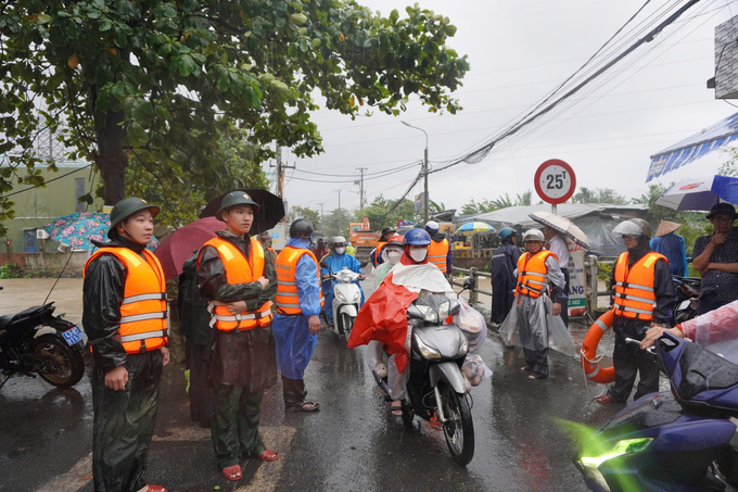 Lực lượng chức năng hướng dẫn người dân đi lại ở các khu vực bị ngập nước. Ảnh: A.N.