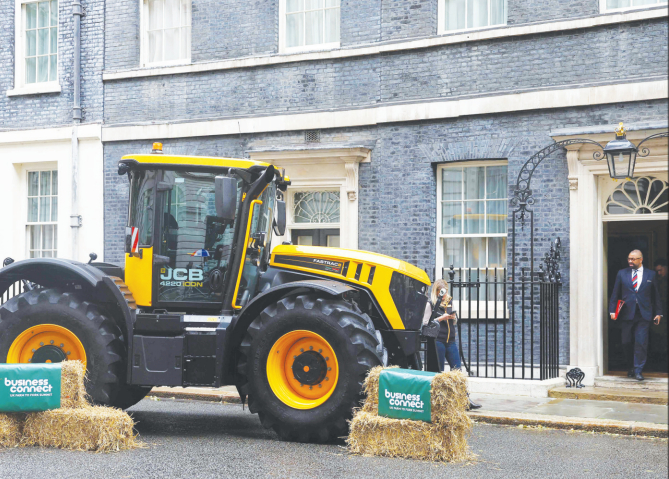 Former Britain's home secretary James Cleverly looks towards a tractor, which promotes the Farm to Fork summit organized by the UK government, as he leaves 10 Downing Street on May 14. Photo: AFP.