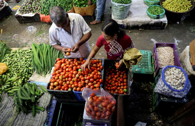 A woman selects tomatoes from a vegetable vendor, at a wholesale market in Navi Mumbai, India August 4, 2023. 