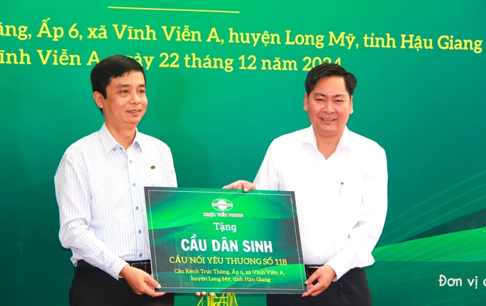 Ông Trần Ngọc Bảo - Thành viên Hội đồng quản trị, Phó Tổng Giám đốc Công ty Nhựa Tiền Phong (bên trái) trao bảng tượng trưng tặng cầu dân sinh cho ông Nguyễn Vũ Trường - Chủ tịch UBND huyện Long Mỹ (bên phải). Ảnh: Kim Anh.