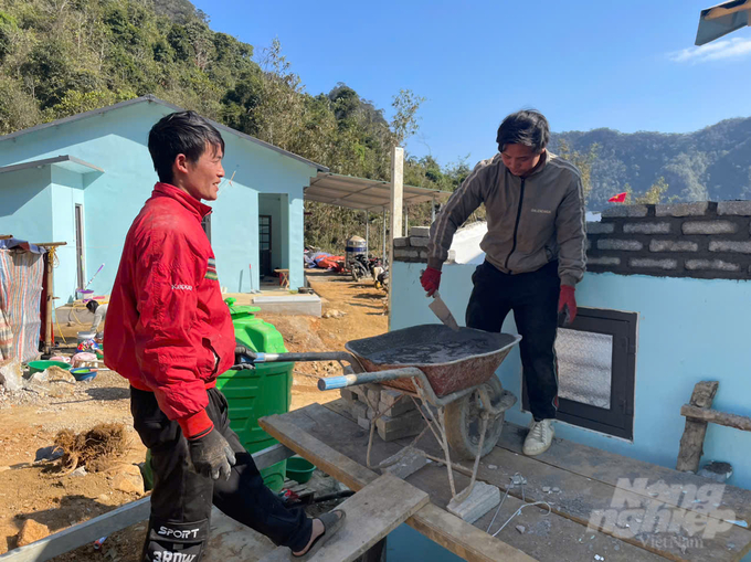 Gần nhà ông Trình, gia đình anh Hoàng Văn Mình (áo đỏ) đang hoàn thiện khu nhà vệ sinh. Anh Mình cho biết, ngoài ngôi nhà được Nhà nước hỗ trợ sẽ làm thêm căn bếp và một phòng ngủ.