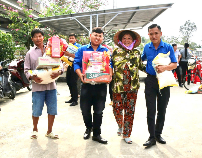 Đoàn viên Đoàn Thanh niên Cộng sản Hồ Chí Minh Trung tâm Khuyến nông Kiên Giang hỗ trợ các hộ dân có hoàn cảnh khó khăn mang quà Tết về nhà. Ảnh: Trung Chánh.