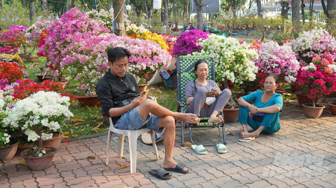 Không khí tại chợ hoa Tết khá lặng lẽ, một số nhà vườn, tiểu thương trò chuyện với nhau trong lúc chờ khách hỏi mua hoa.