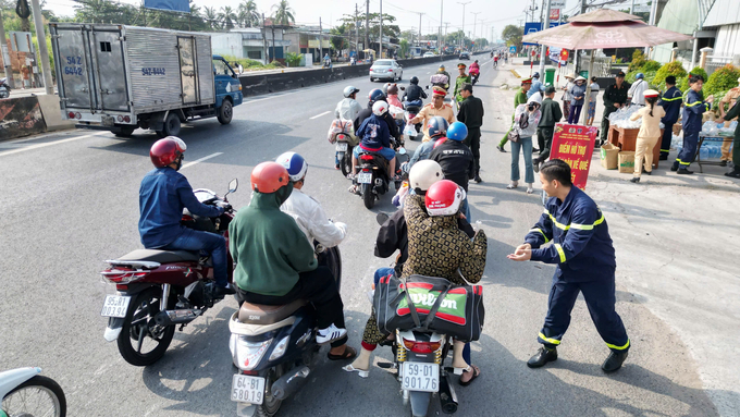 Các chiến sĩ Công an tỉnh Vĩnh Long đang phát nước suối, sữa, khăn lạnh cho người đi đường. Ảnh: HT.