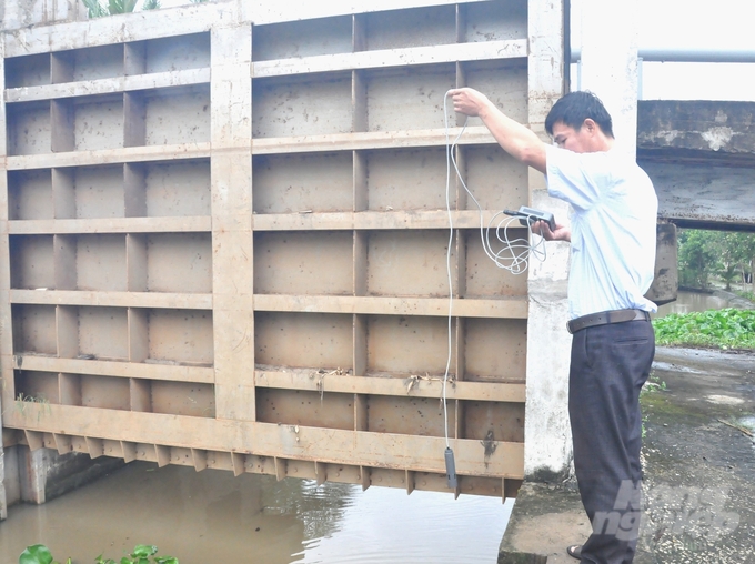 Cán bộ thủy lợi ngành nông nghiệp tỉnh Hậu Giang đo kiểm tra độ mặn tại các cửa cống thuộc hệ thống đê bao Vị Thanh - Long Mỹ để có giải pháp ngăn mặn xâm nhập sâu vào nội đồng. Ảnh: Trung Chánh.