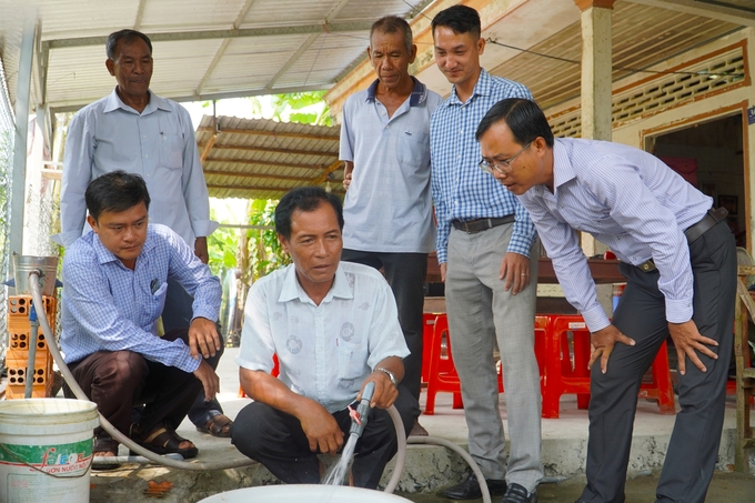 Ông Nguyễn Thế Lâm, Phó Giám đốc Trung tâm Nước sạch và Vệ sinh môi trường nông thôn TP Cần Thơ (ngồi bìa trái) cùng lãnh đạo địa phương kiểm tra việc chất lượng nước sạch cung ứng cho người dân. Ảnh: Kim Anh.