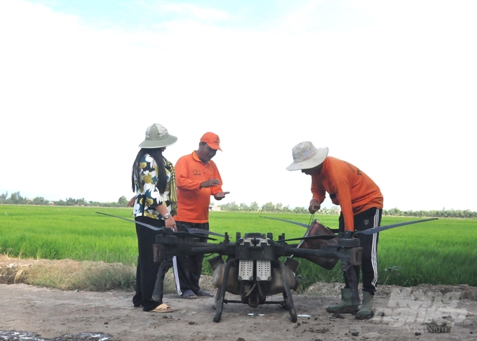 Nông dân Nguyễn Thanh Tuấn đang trao đổi với cán bộ kỹ thuật của trang trại về chăm sóc, bảo vệ cây lúa trước dịch hại. Ảnh: Trung Chánh.