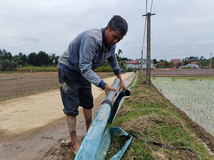 Ông Khôi đấu nối đường ống để bơm nước về ruộng. Ảnh: Thanh Tiến.