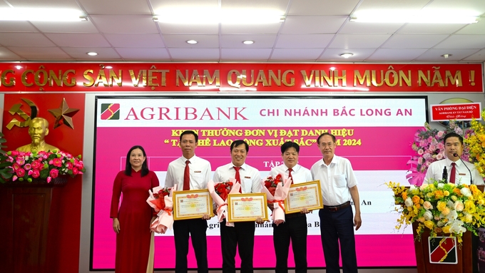 Ông Bùi Thanh Quang - Trưởng Văn phòng đại diện Agribank khu vực Tây Nam bộ (bìa phải) và bà Trần Thị Phế - Phó Giám đốc Agribank chi nhánh Bắc Long An (bìa trái) trao giấy khen và hoa cho các đơn vị đạt danh hiệu 'Tập thể lao động xuất sắc' năm 2024. Ảnh: Minh Hùng.