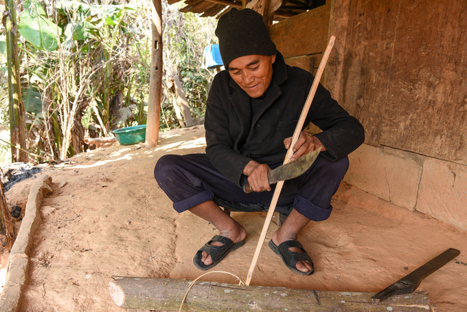 Ông Giàng Bùa Măng đang vót nỏ ngoài sân. Ảnh: Dương Đình Tường.