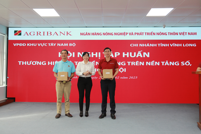 Ông Phan Văn Bá (bên phải) và ông Trương Văn Chuyển (bên trái) nhận quà lưu niệm từ Agribank chi nhánh tỉnh Vĩnh Long, đơn vị đăng cai tổ chức hội nghị. Ảnh: KA.