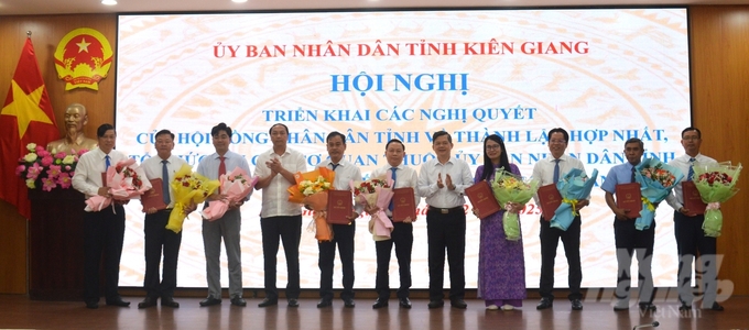 Chủ tịch HĐND tỉnh Kiên Giang Lâm Minh Thành (thứ 4 từ trái qua) và Phó Chủ tịch UBND tỉnh Kiên Giang Giang Thanh Khoa (thứ 5 từ phải qua) trao quyết định và tặng hoa chúc mứng các lãnh đạo sở mới được thành lập, hợp nhất. Ảnh: Trung Chánh. 