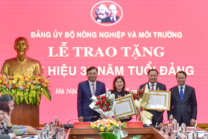 Chủ nhiệm Ủy ban Kiểm tra Đảng ủy Bộ Nguyễn Thị Phương Hoa (thứ hai từ trái sang) và Ủy viên Ban Thường vụ Đảng ủy Bộ Lê Minh Ngân vinh dự đón nhận Huy hiệu 30 năm tuổi Đảng. Ảnh: Tùng Đinh.