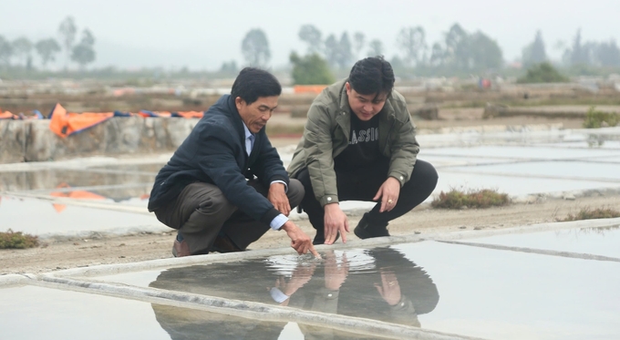 Ông Bùi Xuân Điện (bên trái) đã gắn bó cả đời mình với nghề sản xuất muối truyền thống. Ảnh: Ngọc Linh.