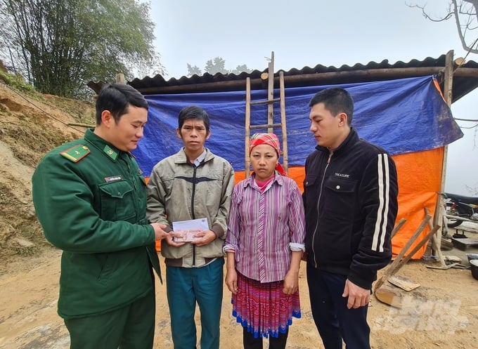 Anh Ma Chẩu Sinh (thứ 2 bìa trái) cùng vợ nhận tiền hỗ trợ đợt đầu tiên từ cán bộ, chiến sỹ Đồn biên phòng Thàng Tín để làm ngôi nhà mới, kiên cố. Ảnh: Đào Thanh.