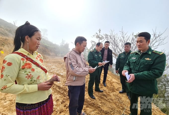 Vợ chồng Vàng Seo Lanh nhận khoản tiền hỗ trợ đầu tiên để làm ngôi nhà mới từ cán bộ, chiến sỹ Đồn biên phòng Thàng Tín. Ảnh: Đào Thanh.