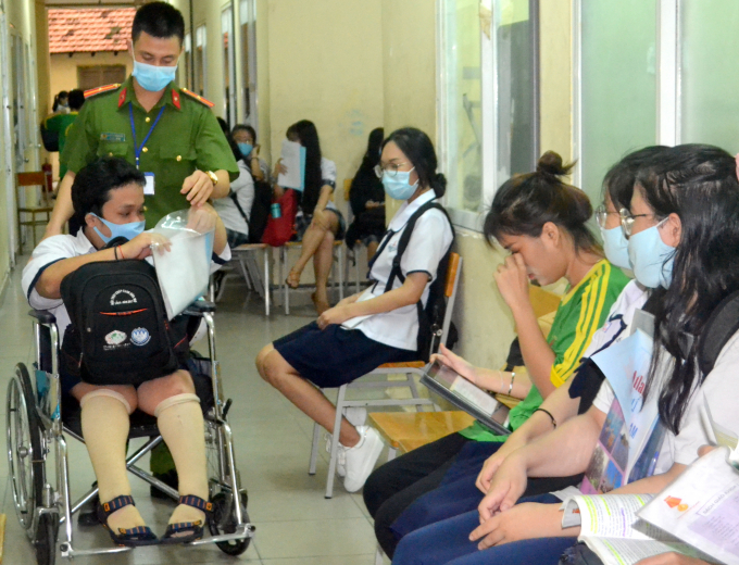 Một chiến sĩ công an giúp thí sinh khuyết tật vào phòng thi tại Trường THPT Phan Đăng Lưu, quận Bình Thạnh, TPHCM. Ảnh: Trần Trung.