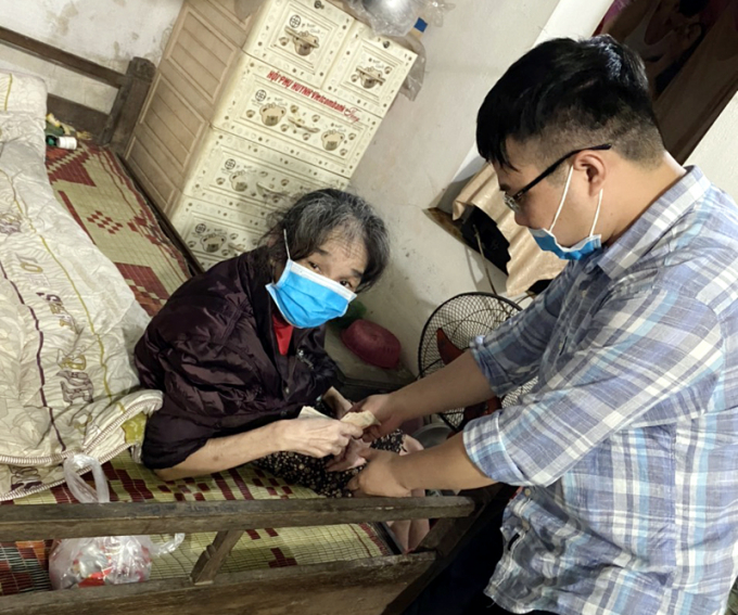 Cán bộ Phòng LĐ-TB&XH huyện Tiên Yên chi trả phụ cấp tạm ứng hỗ trợ trước 2 tháng cho cụ Nguyễn Thị Liễu (100 tuổi), phố Thống Nhất, thị trấn Tiên Yên. Ảnh: Báo Quảng Ninh.