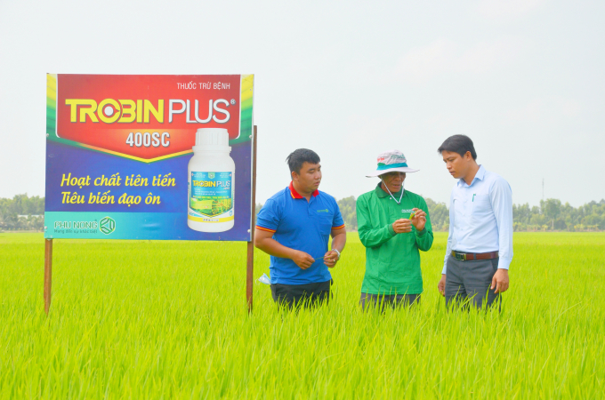 Tư vấn kỹ thuật của Công ty TNHH Phú Nông tư vấn cách sử dụng sản phẩm Trobin Plus phòng trừ đạo ôn trên cây lúa cho ông Bảy Ai. Ảnh: Minh Đảm.