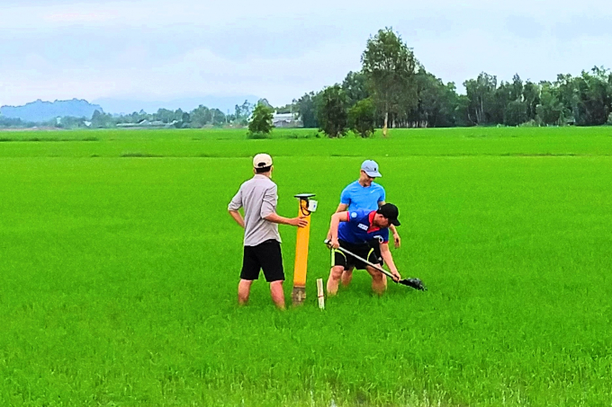 Nhóm nghiên cứu hỗ trợ nông dân lắp đặt thiết bị đo mực nước trên ruộng. Ảnh: ĐH Trà Vinh.