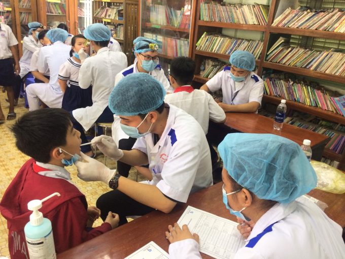 Sinh viên ĐH Trà Vinh và các bác sỹ chuyên khoa Nhật Bản khám răng cho học sinh tiểu học TP Trà Vinh. Ảnh: Minh Đảm.