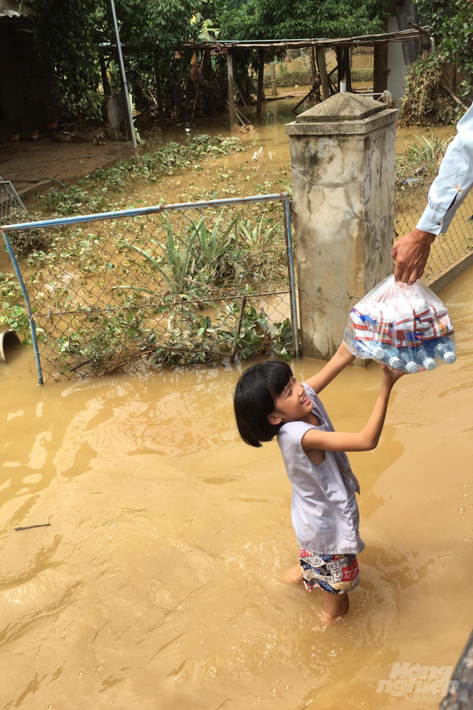 Một em nhỏ nhận gói quà gồm mỳ gói và nước lọc. Ảnh: Hải Yến.