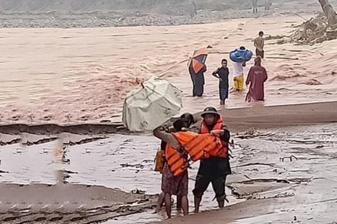 Cán bộ chiến sĩ Đồn Biên phòng Cửa khẩu quốc tế La Lay đưa sản phụ vượt qua cầu tràn trong mưa lũ. Ảnh: Phan Vĩnh.