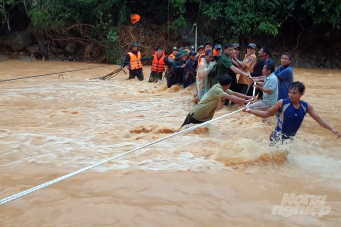 Do nước lũ đang dâng cao, chảy xiết nên đoàn cứu hộ phải sử dụng sợi dây thừng nối 2 bờ suối để đảm bảo an toàn. Ảnh: Phan Vĩnh.
