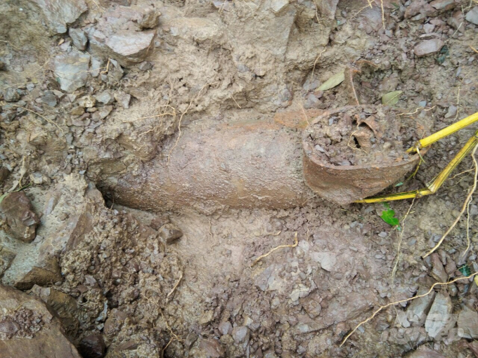  Một phần quả bom lộ ra sau đợt mưa lũ ởkhu dân cư bản A Rong. Ảnh: A Ngo.