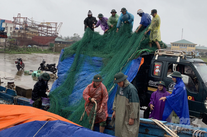 Cán bộ, chiến sĩ Biên phòng Quảng Trị giúp người dân thu dọn ngư lưới cụ lên bờ. Ảnh: Phan Vĩnh.