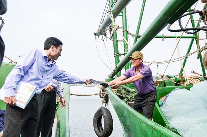 Cán bộ Sở NN-PTNT Quảng Trị phát tờ rơi tuyên truyền về chống khai thác IUU cho ngư dân. Ảnh: Tâm Phùng.