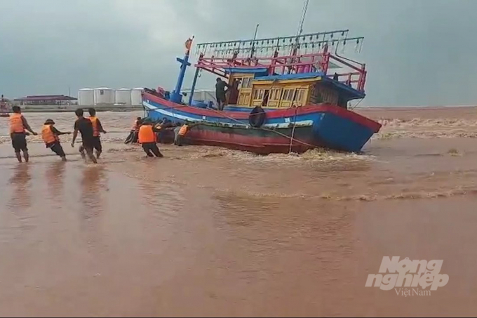 Lực lượng cứu hộ vật lộn với sóng gió để đưa tàu cá vào bờ. Ảnh: Phan Vĩnh.