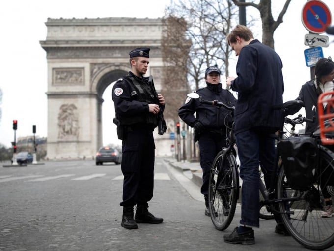 Cảnh sát Pháp kiểm tra giấy phép một người đi xe đạp trước Khải Hoàn Môn hôm 18/3. Ảnh: Reuters