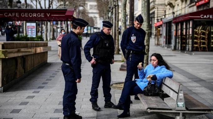 Cảnh sát nhắc nhở một du khách trên đại lộ Champs-Elysée ngày 17/3 sau khi lệnh giới nghiêm có hiệu lực. Ảnh: AFP