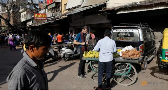 Một du khách mua chuối bán rong ngay trước giờ phong tỏa ở New Delhi. Ảnh: Reuters