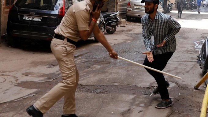 Một cảnh sát cầm dùi vụt người đàn ông vi phạm lệnh phong tỏa tại New Delhi hôm 25/3. Ảnh: RT