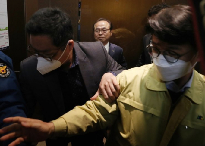 Hình ảnh ông Oh (phía sau) rời khỏi buổi họp báo thừa nhận tội lạm dụng tình dục. Ảnh: Yonhap