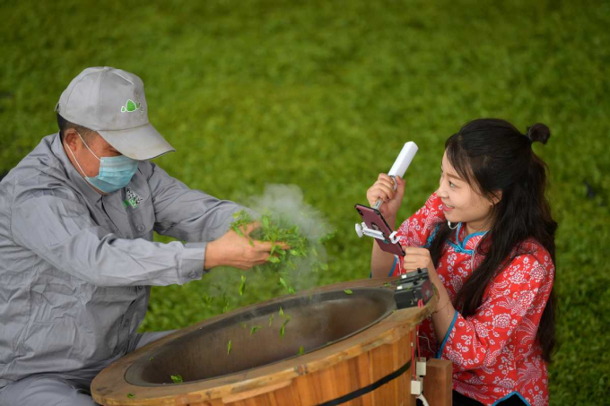 Một công nhân nhà máy chè ở huyện Hạc Phong, tỉnh Hồ Bắc đang biểu diễn công nghệ ướp trà để livestream quảng bá đặc sản địa phương. Ảnh: Xinhua