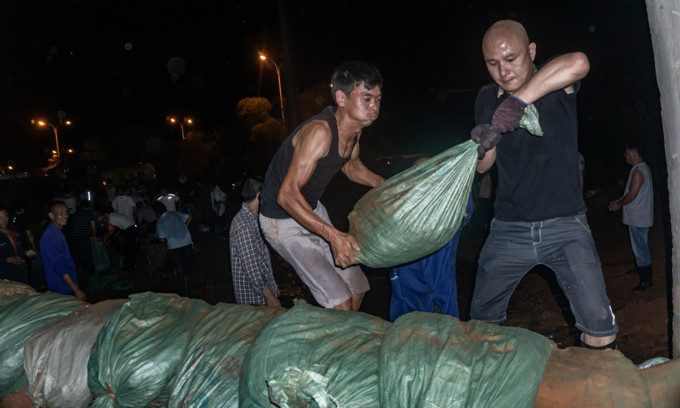 Quần chúng nhân dân ở khu vực hồ Bà Dương, tỉnh Giang Tô xuyên đêm trấn giữ đê kè bằng bao cát để ngăn nước lũ. Ảnh: GlobalTimes