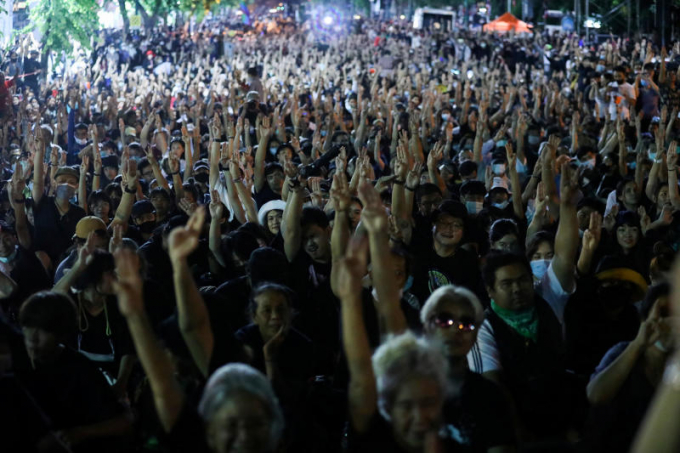 Đám đông người biểu tình chặn đoàn xe chở Hoàng hậu Suthida và ra dấu ba ngón tay mang thông điệp 'hãy cút đi'. Ảnh: Reuters