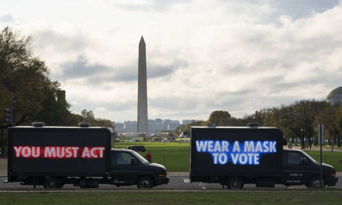 Hai chiếc xe bít bùng mang thông điệp sức khỏe cộng đồng băng qua Đài tưởng niệm Washington trước khi diễn ra Ngày Bầu cử Mỹ. Ảnh: Xinhua
