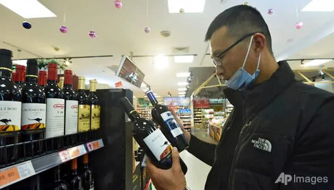 Một người đàn ông Trung Quốc so sánh hai chai rượu vang Úc tại một siêu thị ở Hàng Châu, tỉnh Chiết Giang hôm 27 tháng 11 năm 2020. Ảnh: AP