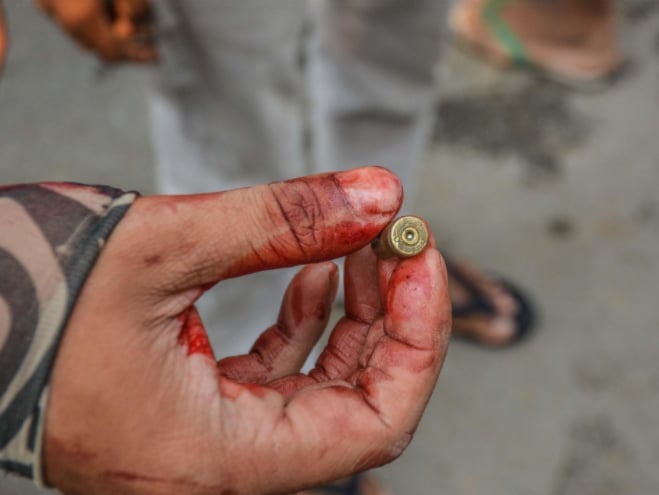 Một người biểu tình nhặt một viên đạn dính máu trên đường phố Mandalay, trong ngày 27 tháng 3 năm 2021. Ảnh: Kyodo